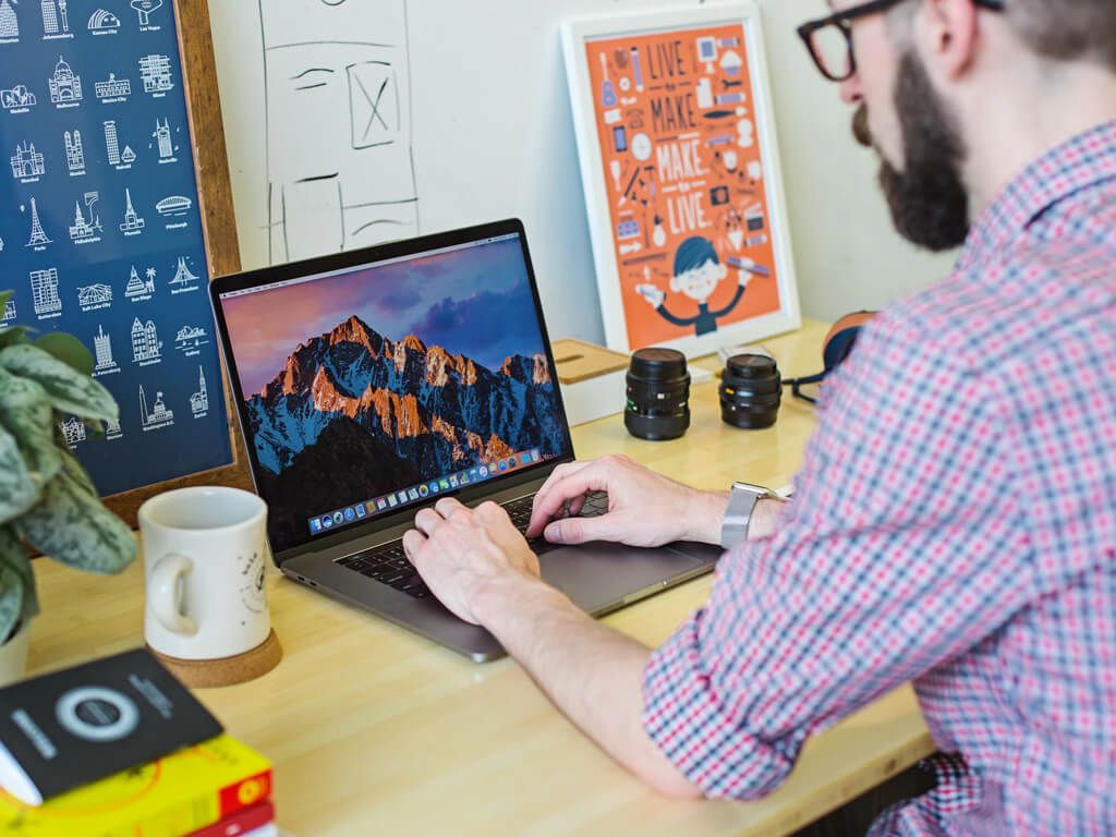 Designer working on brand visuals at a laptop on a tidy desk